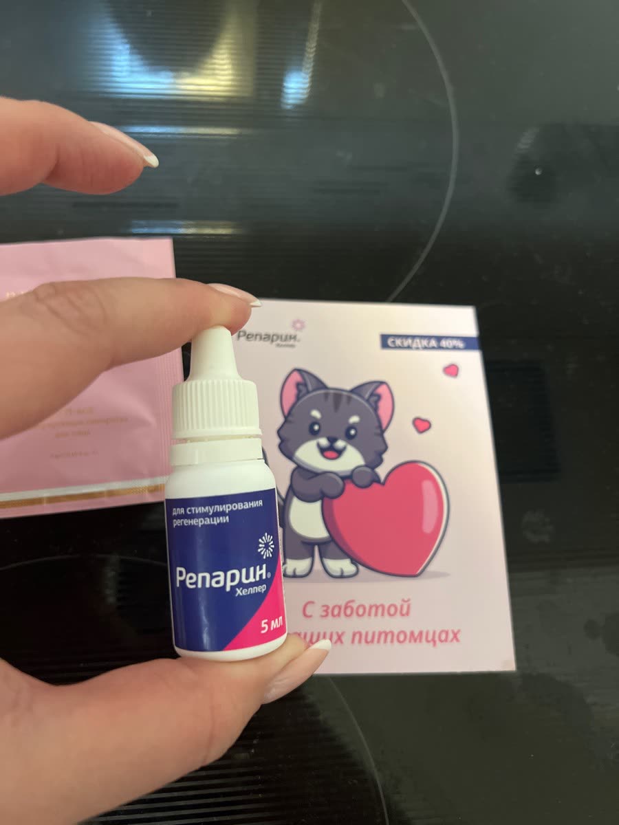 Флакон ветеринарного средства держат на фоне упаковки с рисунком кота.